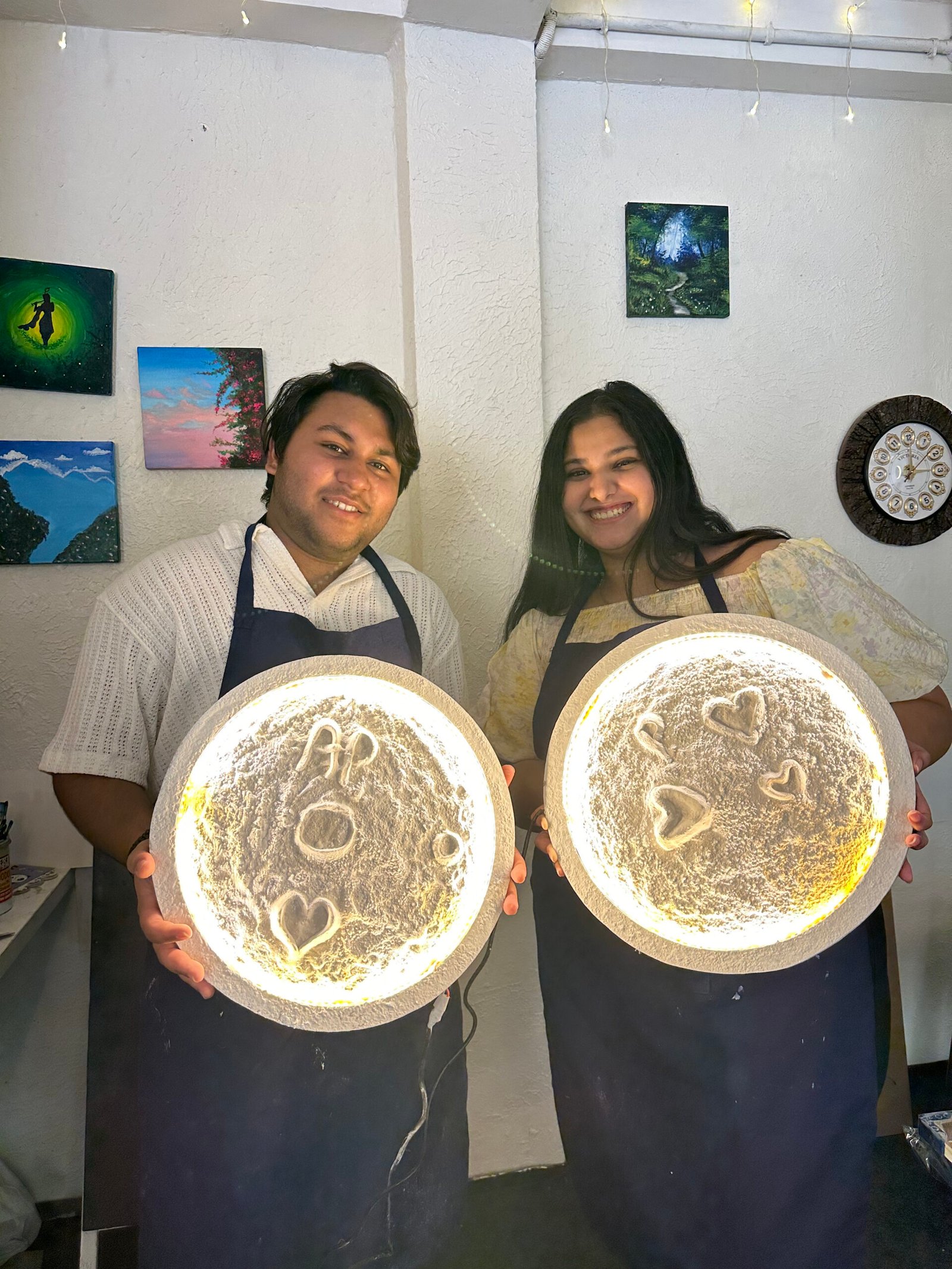 Couple holding their glowing moon art creations during a Chalkbooard workshop.